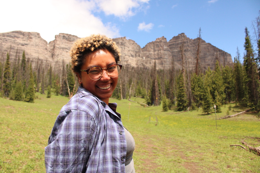 Faith smiling in front of a mountain landscape