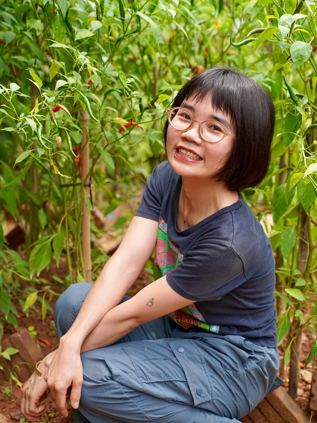 Ly sitting in green plants and smiling